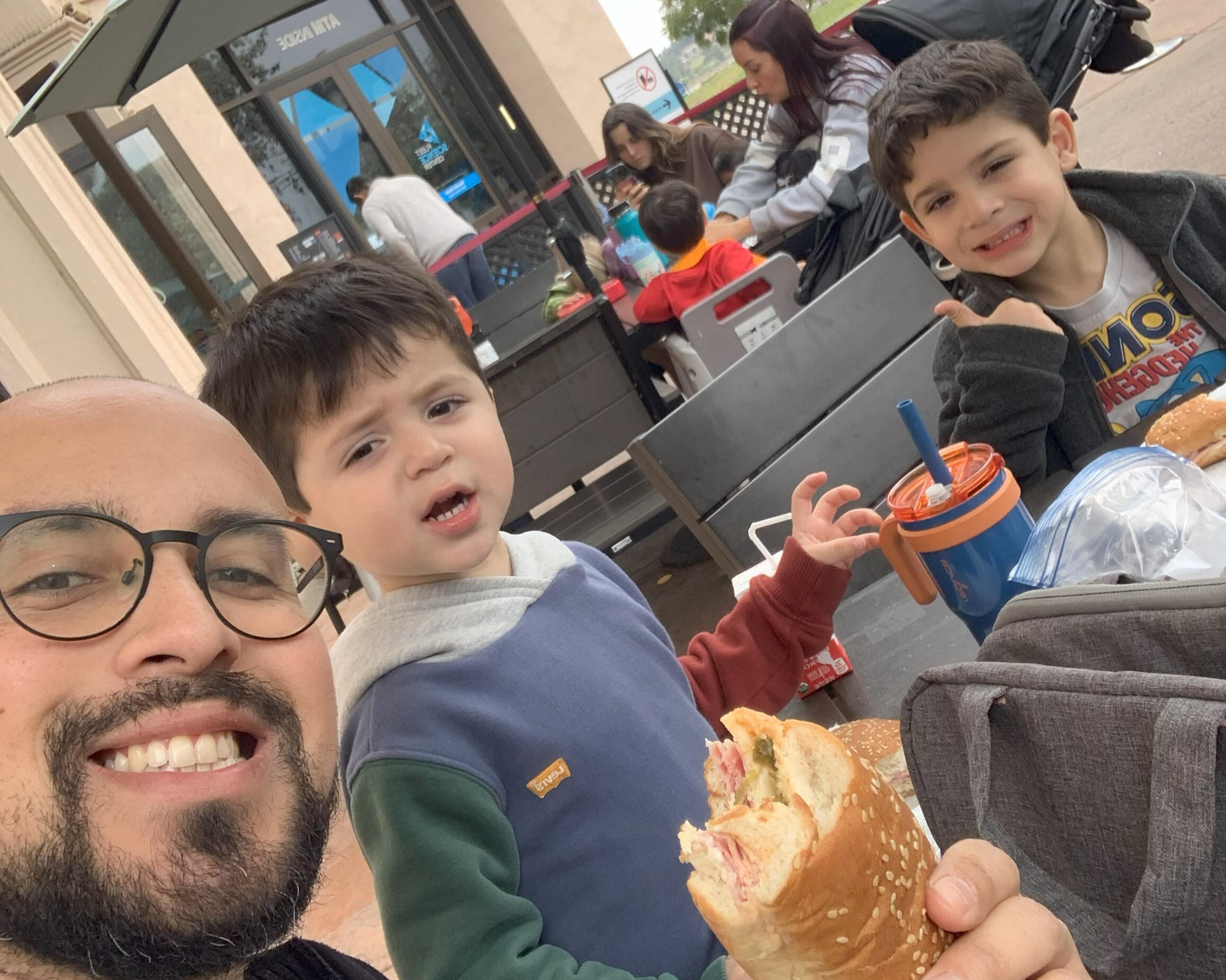 Founder's Sons A selfie of the founder, Michael Cuellar, with his two sons eating lunch at an outdoor table.